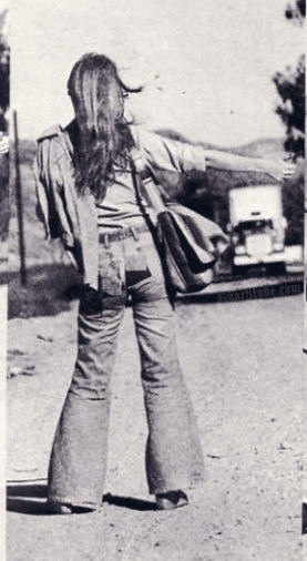 A young woman hitchhiking by the side of the road